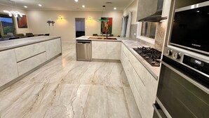 A modern kitchen with a built-in dishwasher, a Samsung oven, and a large island with seating. - Luxury 5BR Lakefront Homestead — 55 Acres, Sandy Beach, Firepit (Oberon)