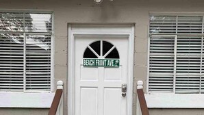 A front door with a nameplate reading 'BEACH FRONT AVE.' and a welcome mat.