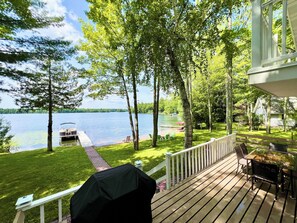 Una terrazza con barbecue, mobili da esterno e vista su un lago.