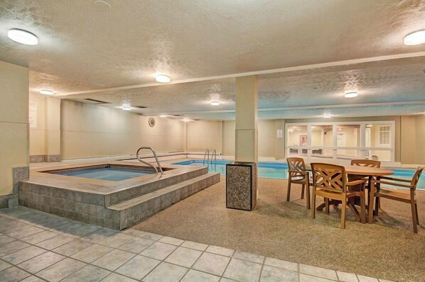 A spa area with a hot tub, a pool, and a dining area with wooden furniture. - Longbranch 309 (Breckenridge)