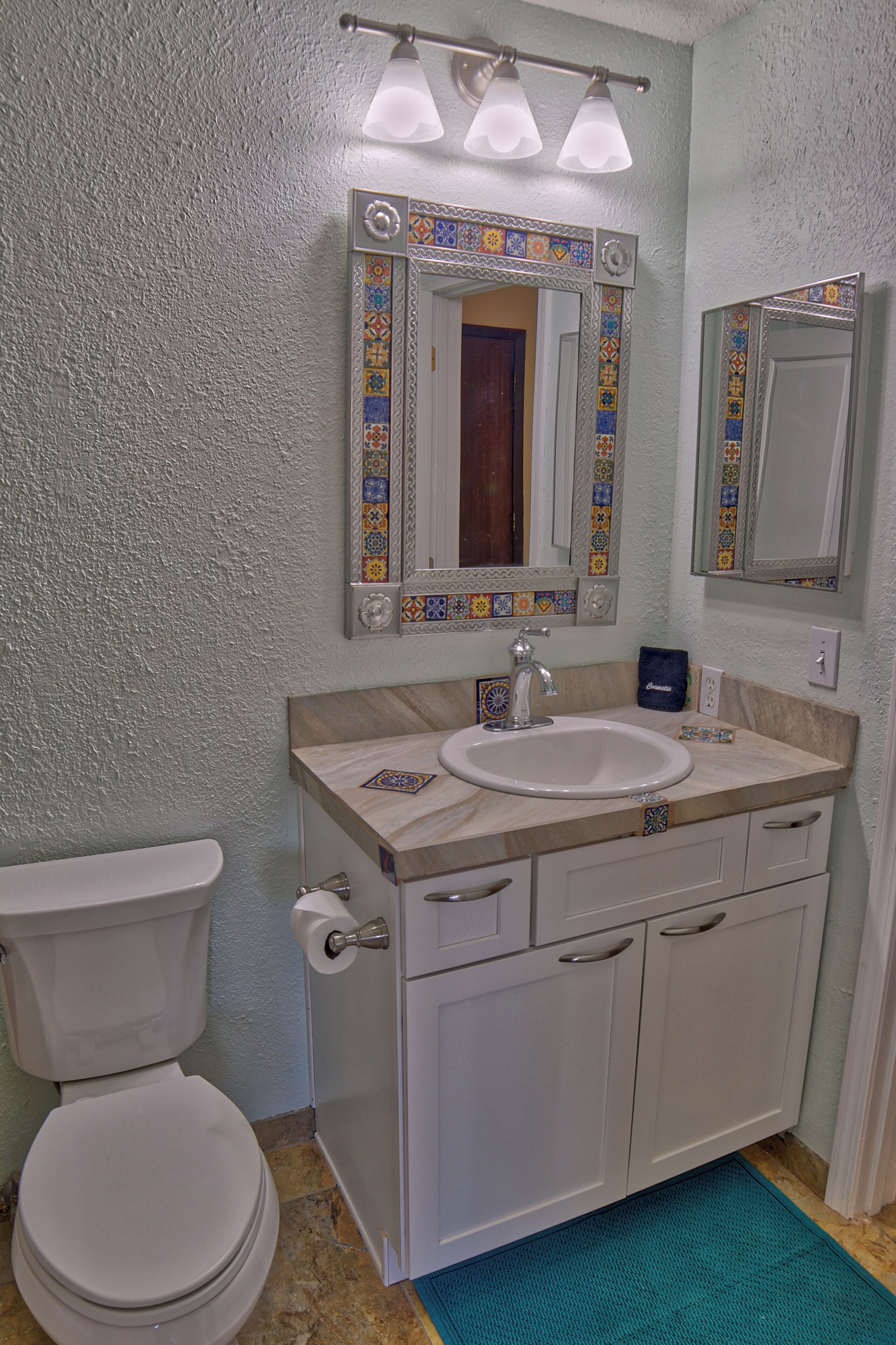 A bathroom with a toilet, sink, and mirror.