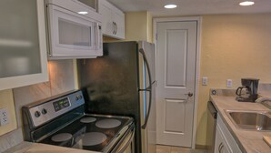 Uma cozinha equipada com fogão, micro-ondas, geladeira e pia.