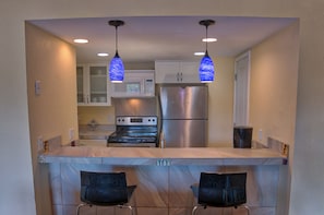 A kitchen with a central island, stainless steel appliances, and blue pendant lights. - Longbranch 309 (Breckenridge)