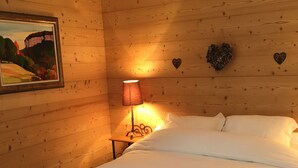A wooden-paneled room with a bed, a lamp, and a painting on the wall.
