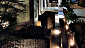 Ein modernes Haus mit überdachter Terrasse, Deckenventilator und einem mit Kerzen gesäumten Weg.