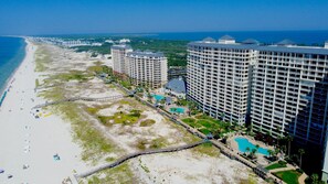 A beachfront hotel with multiple high-rise buildings, a sandy beach, and a swimming pool area. - Luxurious beach front 3 BR condo, Bristol 1007, New Updates! Use our Beach Gear! (Gulf Shores)