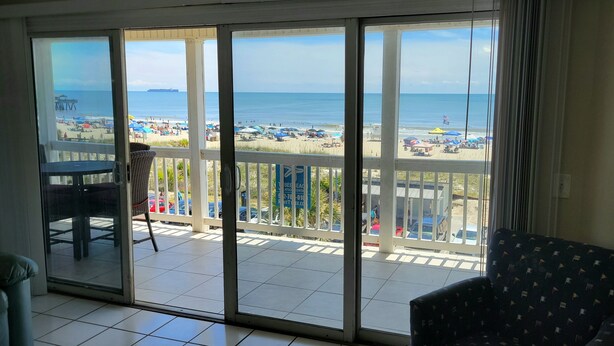 Un balcó amb vista a una platja, una cadira i un moble.