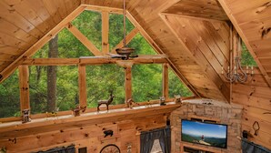 Una cabaña de madera con un ventanal grande, chimenea y televisor.