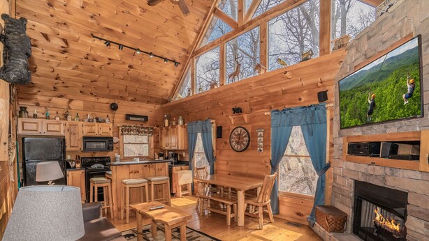 Interior acogedor de una cabaña con comedor de madera, cocina y chimenea.