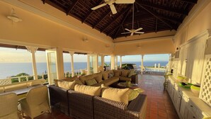 A covered outdoor seating area with a wicker sofa, a dining table, and a view of the ocean. - Villa Albatross Nest with Stunning Panoramic Sea View (Gros Islet)