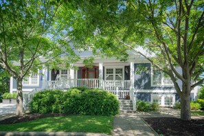 A two-story house with a front porch, a small front yard, and a tree in front. - Waterfront House in the center of the village (Douglas)