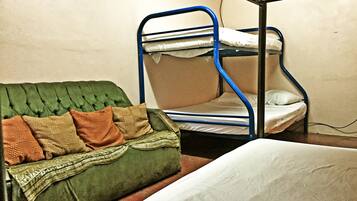 A bunk bed with a green upholstered headboard and pillows, a single bed with white bedding, and a wall socket.