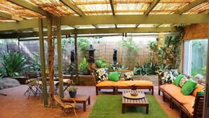 A covered patio area with seating, a small table, and potted plants. - A Great Family Place in Henley Beach - Pets  ✅ opposite park stylish & comfy (Henley Beach)