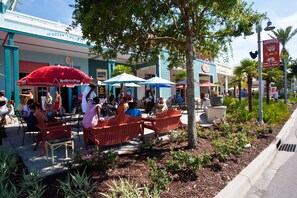 An outdoor seating area with tables and chairs, surrounded by a garden with plants and flowers. - 1PM Early Check In! Beachfront! Walk to Pier Park!  Beach Chair Service included (Panama City Beach)