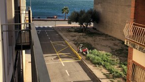 A street view with a clear view of the sea, a parked scooter, and a pedestrian crossing. - COZY APARTMENT 50 M FROM THE BEACH with WIFI (L'Ampolla)