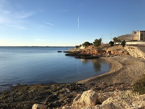 A coastal landscape with a rocky shoreline, calm sea, and a clear sky. - COZY APARTMENT 50 M FROM THE BEACH with WIFI (L'Ampolla)