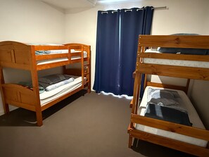 A room with two bunk beds, a curtain, and a light fixture.