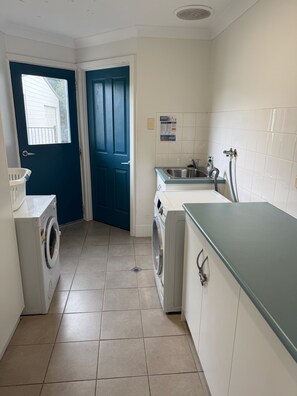 A laundry room with a washing machine, dryer, and a sink with a hose.
