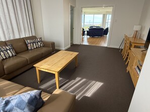 A living room with a sofa, a coffee table, and a dining area with chairs and a table.