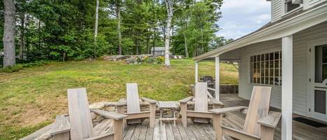 A wooden deck with Adirondack chairs and a stone wall.