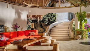 Un vaste espace de vie agrémenté d’un canapé rouge, d’une table basse en bois et d’un escalier menant à un niveau supérieur.