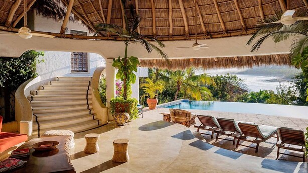 Un espace extérieur luxueux doté d’une piscine, de chaises longues et d’un escalier menant à un niveau supérieur.