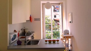A compact kitchen with a sink, a microwave, and a small dining area with a table and chairs. - Historical apartment in Alfama (Lisboa)