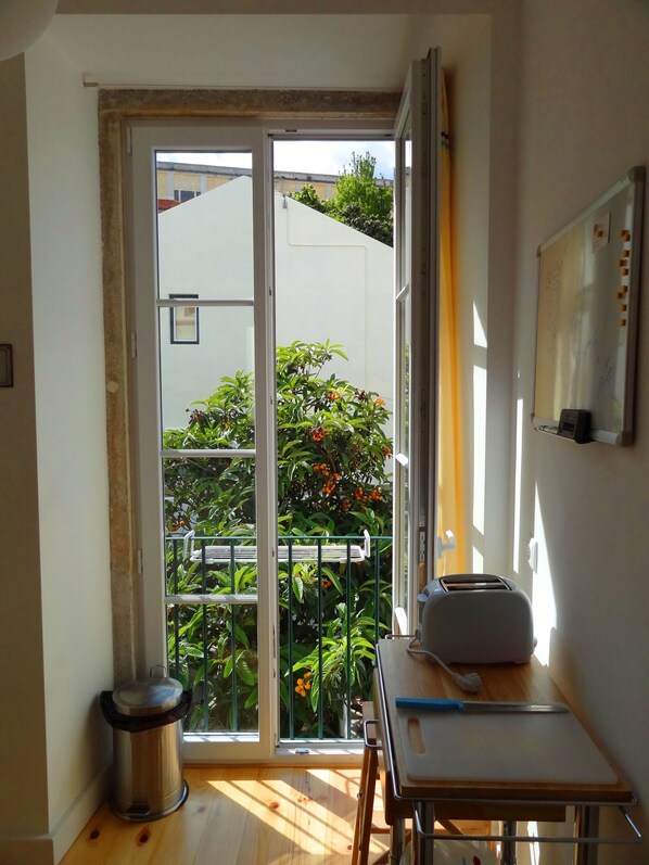 Enjoy a room with a sliding glass door leading to a balcony featuring lush plants and a view of neighboring buildings.