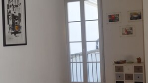 A room with a large window, a white cabinet with drawers, and a framed artwork on the wall. - Historical apartment in Alfama (Lisboa)