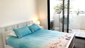 Een slaapkamer met een bed, nachtkastje, airconditioning en uitzicht.