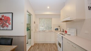 A compact kitchen with white cabinets, a microwave, a stove, and a sink. - SILVER BIRCHES HOLIDAY VILLAGE - UNIT 9 (Bright)