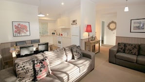 A living room with a sofa set, a dining table with chairs, and a kitchen in the background. - SILVER BIRCHES HOLIDAY VILLAGE - UNIT 9 (Bright)