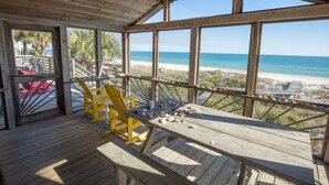 A wooden deck with a table and chairs overlooking a beach. - Beachfront, Plantation, Pet Friendly (Eastpoint)