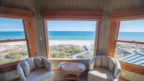 A room with a view of the beach, two striped armchairs, a wicker table with two mugs, and wooden walls. - Beachfront, Plantation, Pet Friendly (Eastpoint)