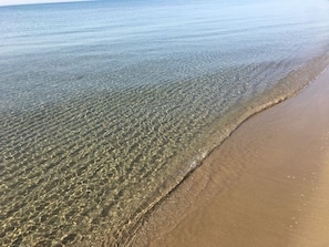 A beach with clear shallow water and a sandy shore.