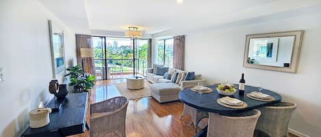 Una sala de estar moderna con comedor, ventanas amplias y vista a la ciudad, además de un balcón.