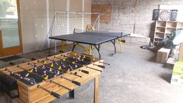 Une pièce équipée d’un baby-foot, d’une table de ping-pong et de cibles de fléchettes.