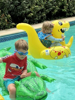 Dos niños sobre flotadores inflables en una piscina.