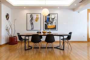 Un coin repas avec une table en bois, des chaises noires et deux œuvres d’art encadrées accrochées au mur.