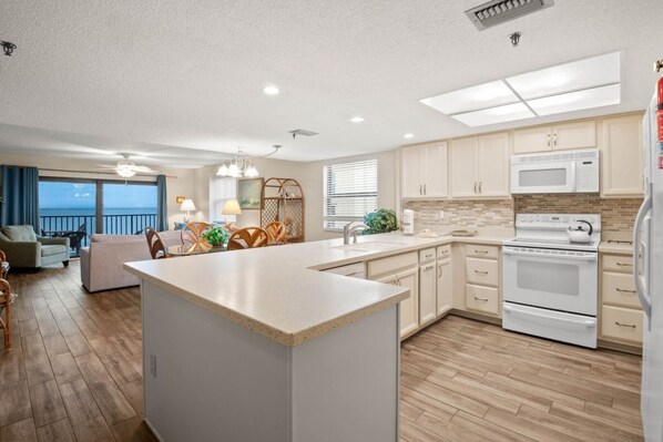 Una cocina moderna con una isla central, armarios blancos, un microondas y una estufa.