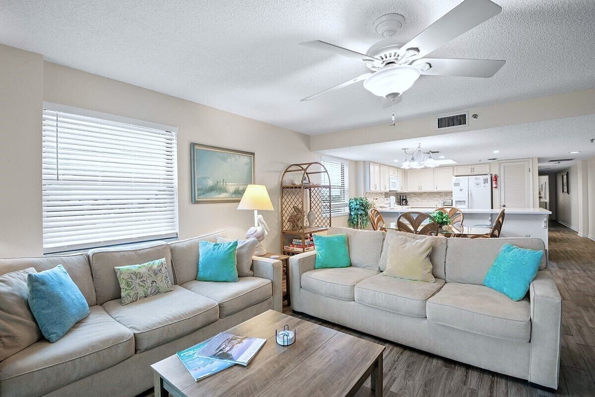 A living room with two sofas, a coffee table, and a ceiling fan.