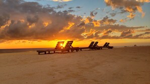 Ein Strand mit Holzbanken, die in einer Reihe zum Meer hin ausgerichtet sind.
