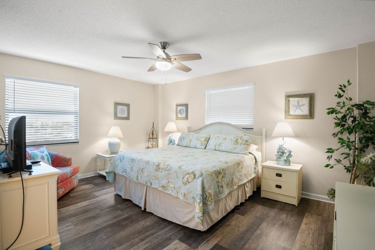 A bedroom with a bed, bedside tables, a ceiling fan, and a television on a stand.