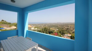 En balkon med et bord og stole, der giver udsigt over et landskab med bygninger og grønt.