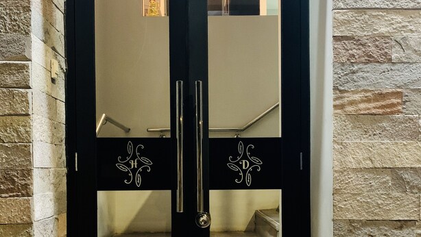A black double door with glass panels and decorative handles, set in a stone wall. - Hotel Daylu Cusco (Cusco)
