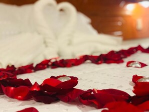 A bed with white linens and scattered rose petals. - Hotel Daylu Cusco (Cusco)