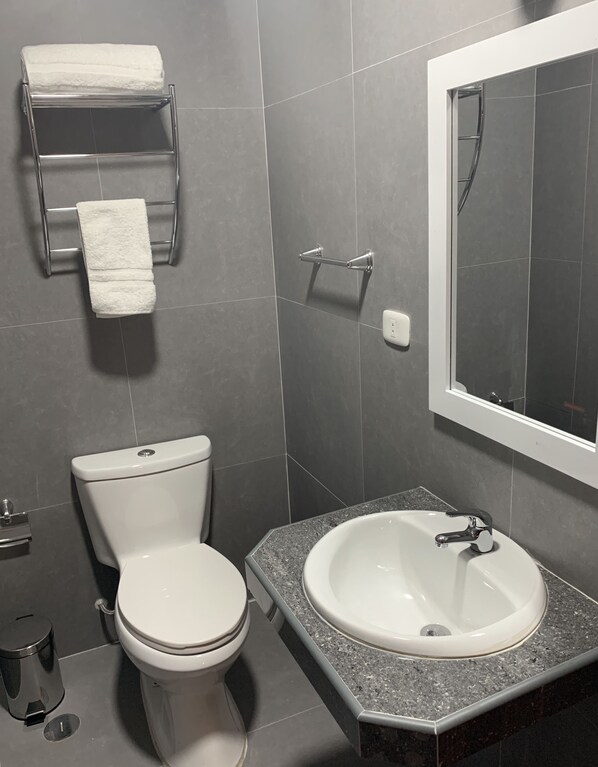 A modern bathroom with a toilet, sink, and towel rack.