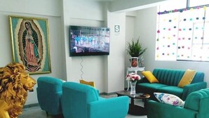 A living room with teal sofas, a television, a statue, and a wall-mounted painting. - Hotel Daylu Cusco (Cusco)