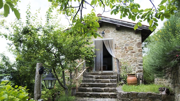 A stone house with a wooden staircase leading to a door with a curtain.