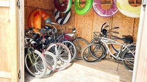 A wooden bicycle storage area with several bicycles and colorful inflatable rings. - Sweet  Victorian Beach Cottage (Cape Charles)